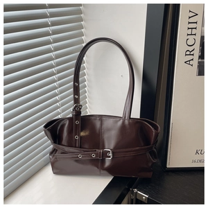 Detail of dark brown faux leather tote with metallic buckles and retro functional style