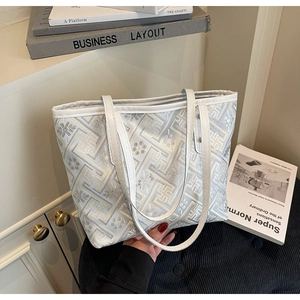 Close-up of a stylish plaid pattern tote bag with white leather straps and artistic books