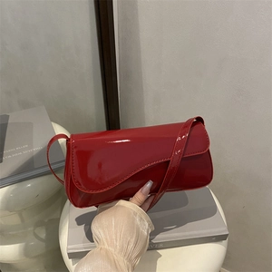 Close-up of vibrant red patent leather crossbody bag with asymmetric curved flap