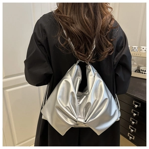 Close-up of a silver bow-shaped tote bag with a metallic finish and black straps