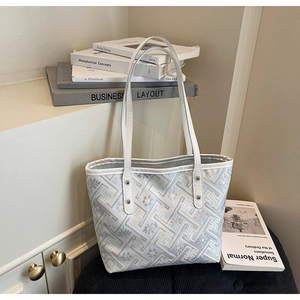 Detail of geometric maze jacquard texture and metallic rivet on white tote bag