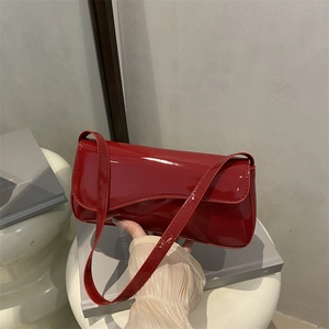 Close-up of bright red patent leather handbag with adjustable strap for daily commute