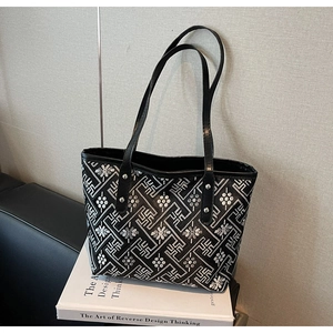 Close-up of geometric pattern embroidery and leather handles on large tote bag