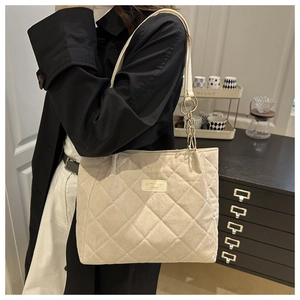 Quilted tote bag detail showing cream fabric with diamond stitching and gold chain