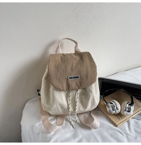 Mini nylon backpack detail with drawstring closure and You Ji Bear logo on bed sheet