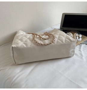 Détail du sac cabas matelassé crème avec chaîne dorée et élégant motif à losanges