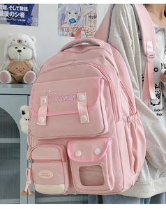 Detail view of the pink student backpack showing front pockets and cushioned straps
