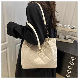 Dettaglio della borsa tote trapuntata beige con catena dorata e placca metallica