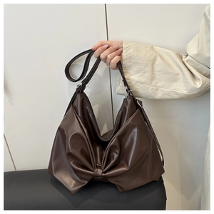 Detail of a dark brown Hobo bag with a large bow design and soft PU leather texture