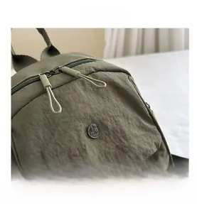 Detail of army green nylon backpack with M FASHION logo and smooth double zipper closure