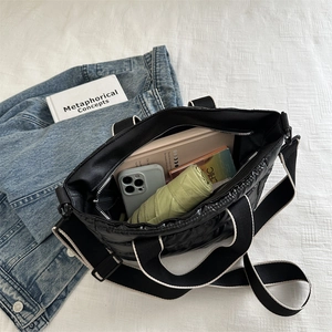 Quilted black nylon tote bag with large capacity showing books and daily essentials