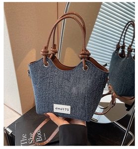 Dettaglio della borsa a secchiello in denim con manici in pelle e occhielli metallici