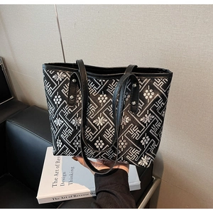 Close-up of patterned black tote bag with silver rivets and textured woven fabric detail