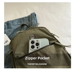 Detail of army green nylon backpack with front zipper pocket for smartphone storage