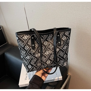 Detail view of black plaid tote bag with silver patterns and floral embroidery