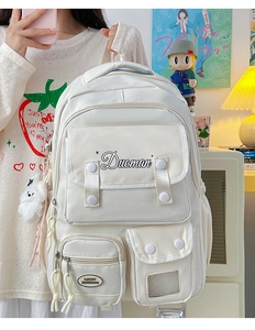 Detailed view of white nylon college backpack with multiple pockets and plush pendant