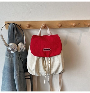 Detail of red and white nylon backpack featuring drawstring closure and top flap design