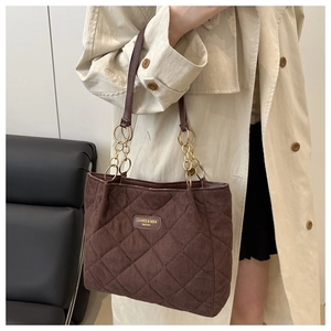 Detail of coffee suede quilted tote bag with metal chain strap and brand logo