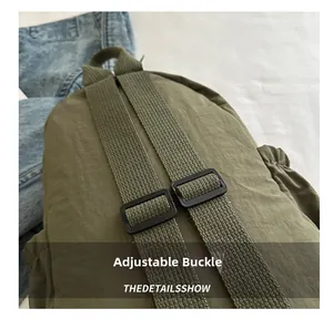 Detail view of adjustable black plastic buckle and nylon fabric strap on green backpack