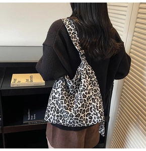 Detail of leopard print canvas tote bag featuring side fashion tag and shoulder strap style