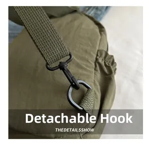 Detail of army green backpack showing matte black detachable hook and durable strap