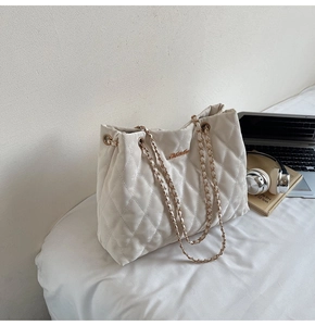 Détail du cabas matelassé beige avec chaînes dorées dans un décor de bureau moderne