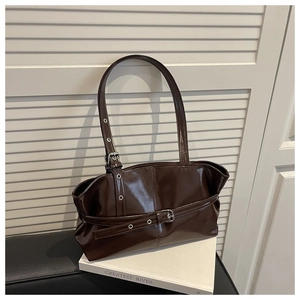 Detailed view of glossy patent leather tote with decorative buckle on a minimalist background