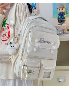 Side view of cream functional backpack with plush bear charm and embroidery detail