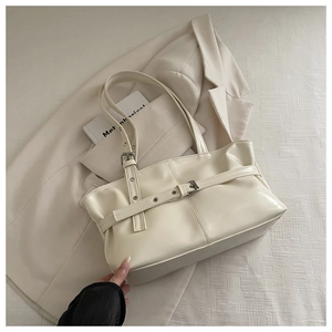 Chic beige tote bag with buckle detail placed on a beige blazer for a minimalist aesthetic