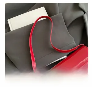 Macro shot of glossy red patent leather shoulder bag with fine matching strap details
