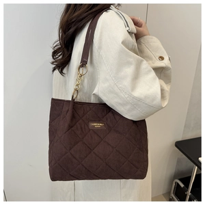 Detail der dunkelbraunen Stepp-Tote-Bag mit goldenem Logo und Leder-Schultergurt