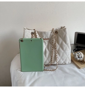 Détail d'un sac cabas blanc matelassé avec ordinateur et accessoires du quotidien