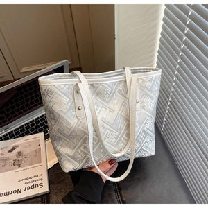 Close-up of embroidered tote bag with geometric patterns and white slim handles
