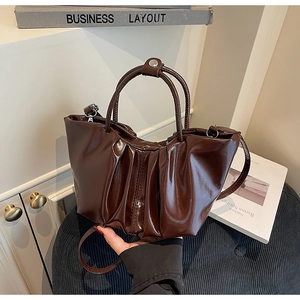 Detail der dunkelbraunen Falten-Handtasche mit glänzendem Lack-Finish und Silberbeschlägen