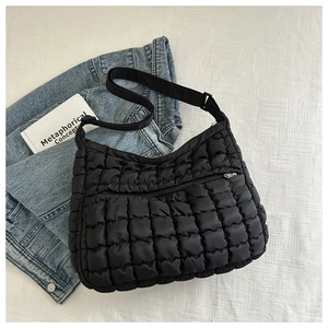Detailed view of black quilted puffer crossbody bag with adjustable wide fabric strap