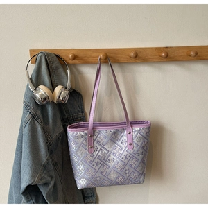 Detail of purple jacquard tote bag with floral patterns on a wooden hook