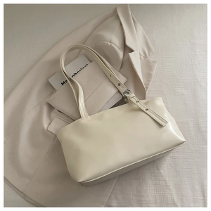 Minimalist beige leather tote bag with adjustable eyelet strap on a cream aesthetic background