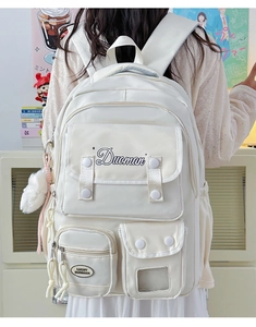 Detailed back view of a beige nylon multi-pocket student backpack with plush ball charm