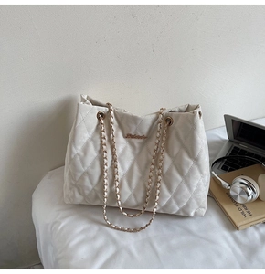 Gros plan du sac cabas blanc matelassé avec bandoulière chaîne et plaque logo dorée