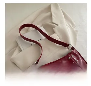 Detail of burgundy glossy leather baguette bag with silver rivet studs on cream blazer