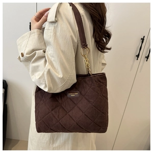 Detail of coffee brown quilted tote bag showing suede texture and shoulder strap