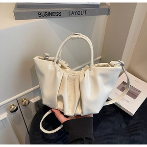 Detail der weichen cremefarbenen Cloud-Bag mit Faltenstruktur und gebogenem Handgriff
