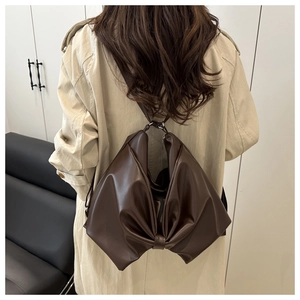 Detail view of a dark brown bow-shaped shoulder bag made of smooth PU leather with slim straps