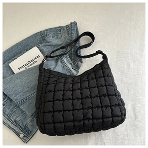 Macro shot of black quilted puff shoulder bag with soft textured grid pattern detail