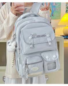Close-up of light blue multi-pocket school backpack with plush pendant and buckle detail