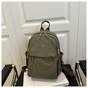 Army green nylon backpack detail showing metal logo and front flap zipper pocket