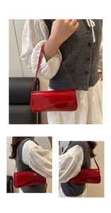 Detail view of red patent leather underarm bag featuring a unique wavy flap design