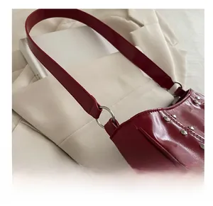 Detail of dark red patent leather shoulder bag with silver rivet studs and metal ring strap
