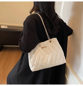 Détail du sac cabas matelassé blanc avec logo doré et bandoulière en chaîne