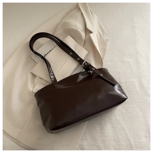 Close-up of glossy brown faux leather shoulder bag with adjustable silver buckle strap